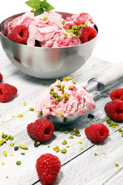 Raspberry ice cream scoop with chopped nuts and white chocolate on a rustic background