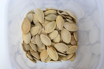 Dry pumpkin seeds in the plastic container