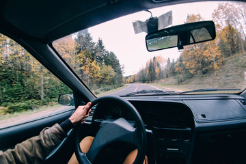 driving a car along a winding forest road in autumn. steering wheel, extreme driving.