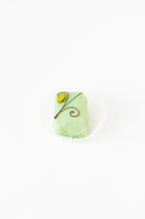Light green petit fours, small cake square, covered with sugar icing and decorated chocolate Christmas ornament and pistachio