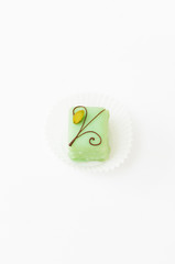 Light green petit fours, small cake square, covered with sugar icing and decorated chocolate Christmas ornament and pistachio