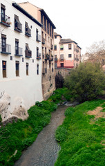 Fototapeta na wymiar Creek passing by the old houses with a balcony facade in the Spanish city of Granada 