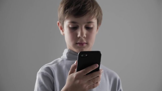 Portrait of Young 11 - 12 year old Boy using Smartphone on white background