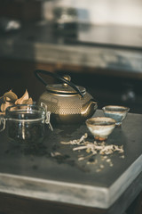 Tea ceremony. Golden iron teapot and japanese ceramic cups on kitchen counter, selective focus. Cold winter morning at home