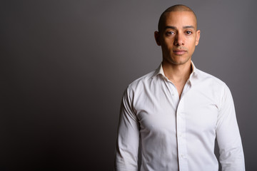 Fototapeta premium Handsome bald businessman looking at camera against gray background