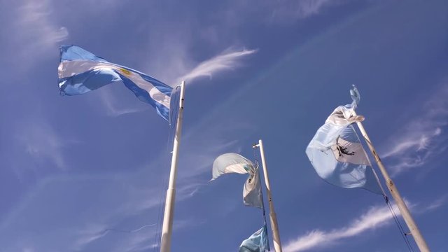 3 flags slowly waving in a blue sky.
3 banderas flameando lentamente en un cielo celeste.