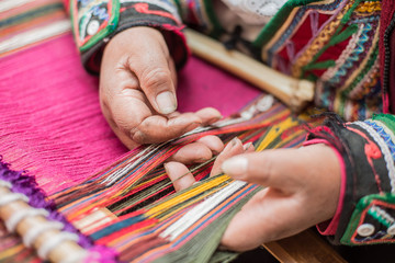 Quechua woman weaving a traditional colorful textile in Cusco city, Perù.