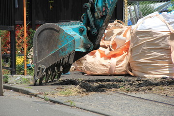 アスファルトで舗装された地面を掘っているショベルカーのバケット部分