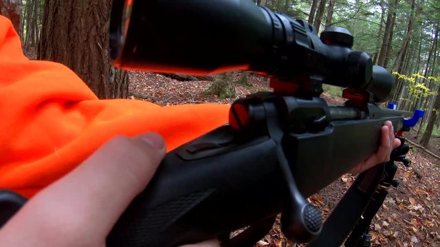 Slow motion footage of young hunter in orange taking his gun off safe