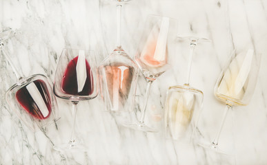 Flat-lay of red, rose and white wine in glasses and corkscrews over grey marble background, top view. Bojole nouveau, wine bar, winery, wine degustation concept