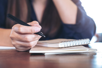 Closeup image of a woman holding a pen to write on wooden table