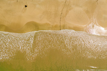 Aerial view of waves breaking on an empty, sandy tropical beach