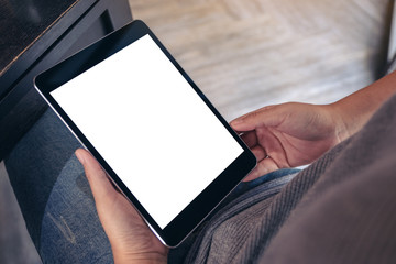 Mockup image of a woman sitting and holding black tablet pc with blank white desktop screen