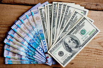 Dollars and tenge on a wooden background. Kazakhstan currency. Business and money..