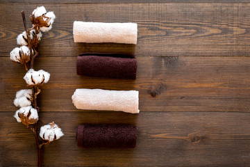 Cotton towels high quality. Set of towels twisted coil near dry cotton flowers on dark wooden background top view space for text