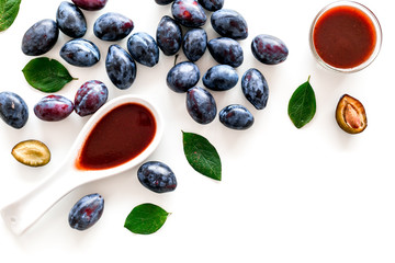 Fresh tkemali sauce. Traditional caucasian, georgian sauce or plum jam in spoon near plums on white background top view copy space