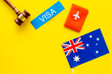 Visa to Australia concept. Text visa near passport cover and australian flag, hammer on yellow background top view copy space