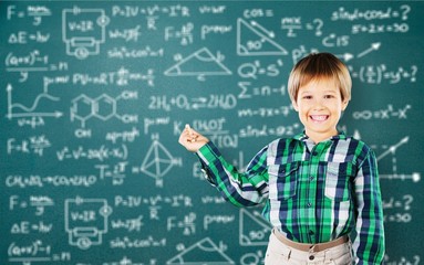 Cute little schoolgirl in glasses on blackboard