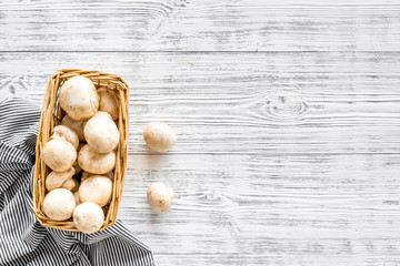 Mushroom champignons. Fresh raw whole champignons in basket on grey wooden background top view copy space