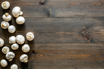 Fototapeta na wymiar Mushroom champignons. Fresh raw whole champignons on dark wooden background top view space for text