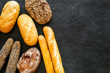 Set of fresh homemade bread. Bread assortment. Loaf, baguette. White and brown bread on black background top view copy space