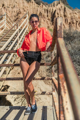 Portrait of latino woman with curly hair, orange jacket and yellow glasses at beach