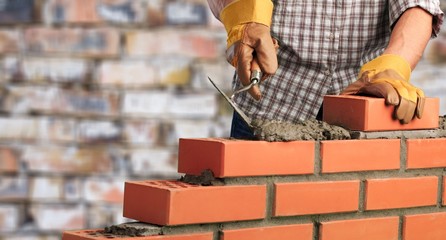Worker builds a brick wall in the