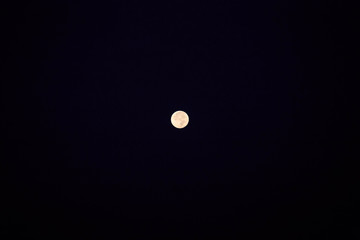Bright full moon shines against dark black background