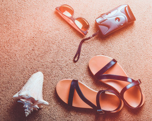 Beach accessories lie on the sand.Camera, sandals, sunglasses, seashells. The concept of relaxing...