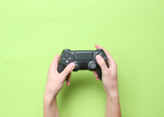 Hands to use the gamepad on green background. Top view.