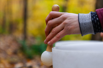 Young Man playing crystal bowls outdoors in the forest while autumn colors are at their best -...
