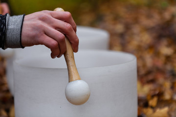 Young Man playing crystal bowls outdoors in the forest while autumn colors are at their best -...