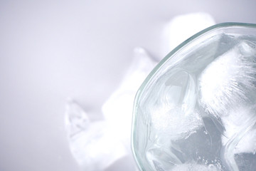 Cold water is in a glass and ice is placed around it. On the white floor. 