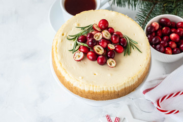 Cheescake with fresh cranberry and rosemary. Christmas cake with decoration on white background.