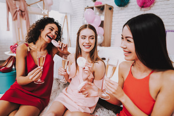 Smiling Girls Sitting on Carpet with Champagne.