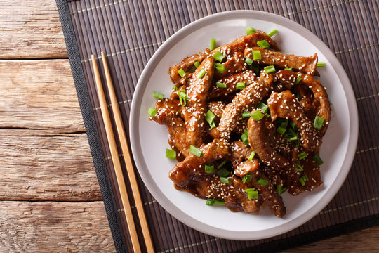Traditional Asian beef teriyaki with green onions and sesame close-up on a plate. Horizontal top view