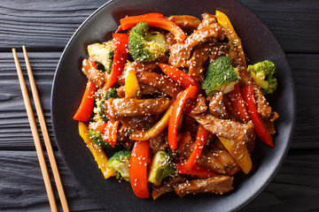 Asian teriyaki beef with bell pepper, broccoli and sesame close-up on a plate. horizontal top view