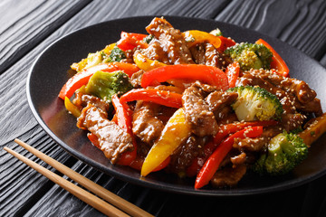 Spicy teriyaki beef with red and yellow bell peppers, broccoli and sesame seeds close-up. Asian...