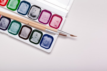 Paper, watercolors, paint brush and some art stuff close up top view