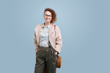Portrait of young cheerful smiling woman in beige cloak with gla