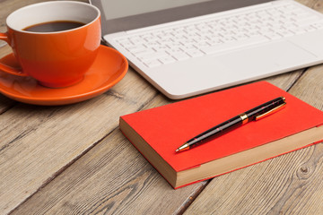 A cup of coffee on the orange plate on the wooden table. Office interior