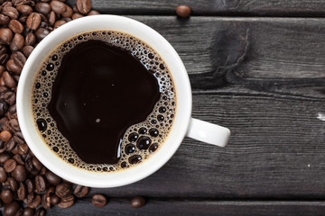 Cup of coffee and beans on wooden background