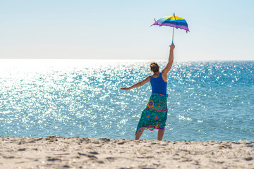 Woman in a pareo with umbrella in hand jumps and having fun