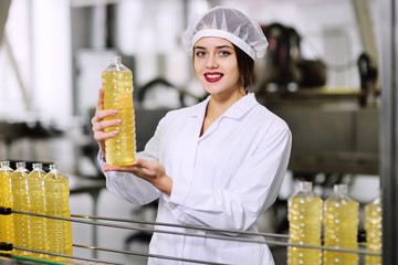 a beautiful young girl in white uniform or a working dressing gown with a bottle of sunflower oil...