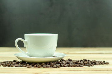 Cup of coffee with coffee beans on wood background.