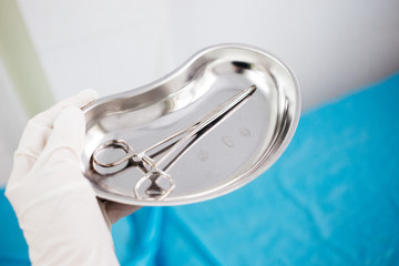 a hand in disposable gloves holding medical instrument in the tray. health, longevity