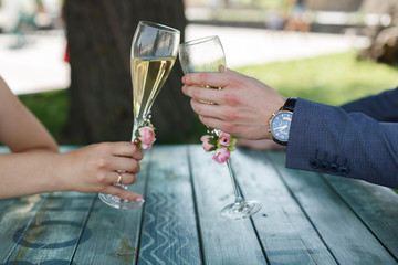 two decorated  glasses with a champagne  in the hands of bride and groom. place of celebration.2 decorated wine glasses .