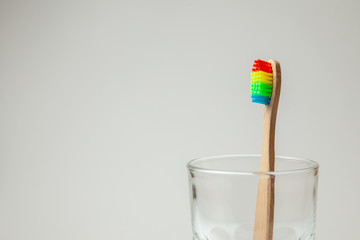 Bamboo toothbrush in glass on gray background.