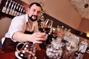 portrait of a handsome bearded barista preparing coffee on the background of a coffee shop and a coffee machine