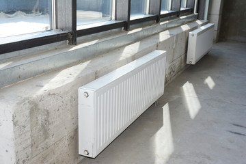 Installing radiators heating in the unfinished house empty room interior.
